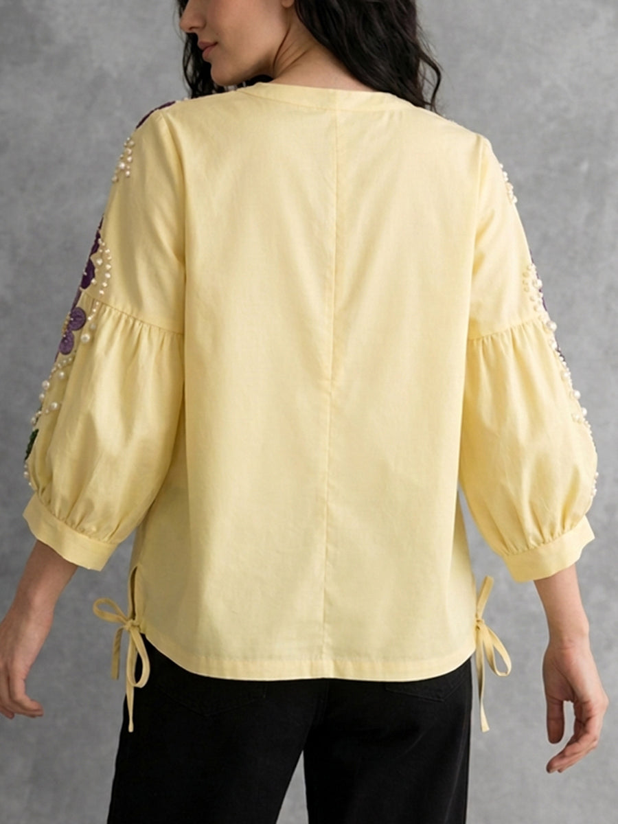 Détail de la blouse jaune femme avec broderies, perles et manches bouffantes