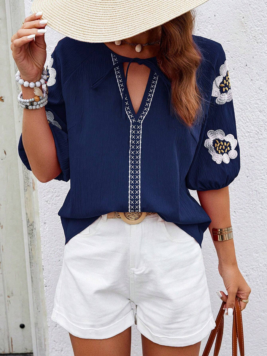 Blouse femme brodée col V à nouer présentée sur fond uni