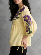 Vue de côté de la blouse femme jaune ample avec détails brodés et liens